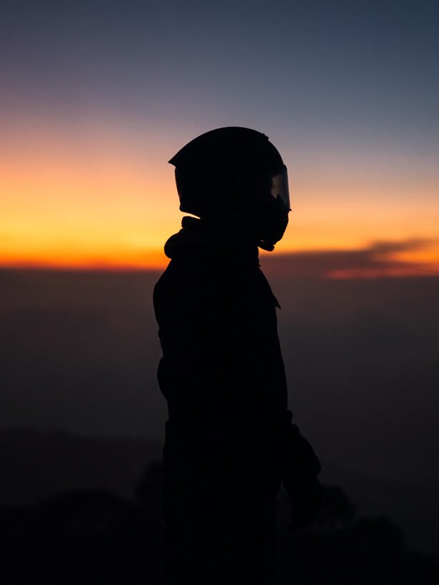 A helmeted rider silhouetted against a sunset sky